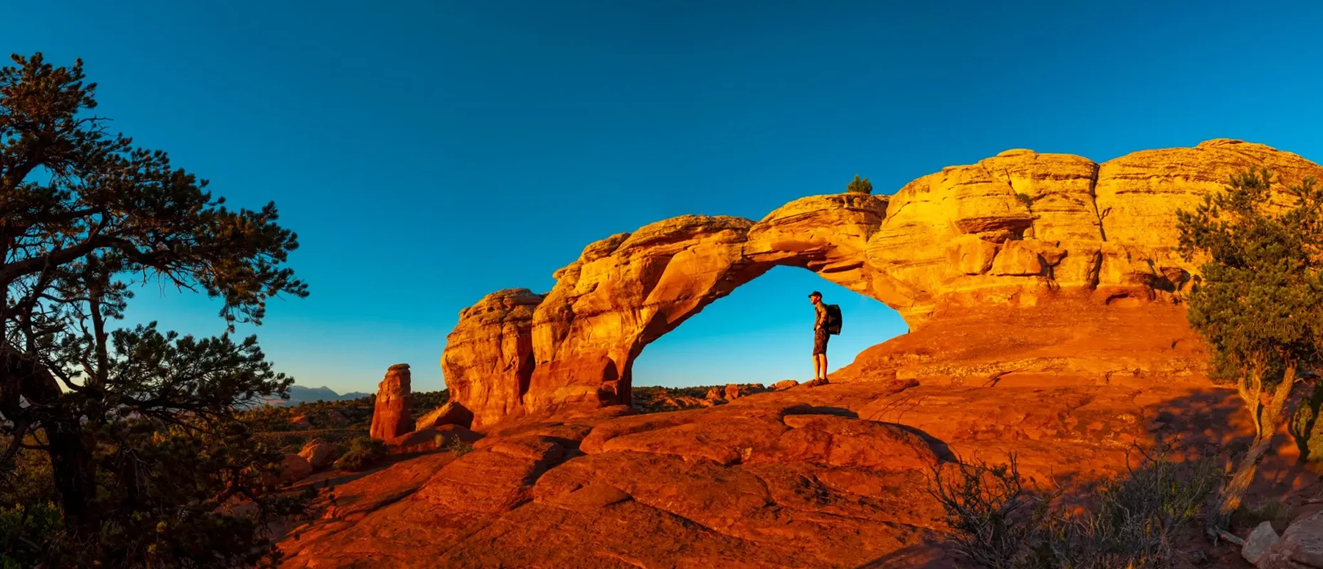 Person standing under natural rock arch formation.